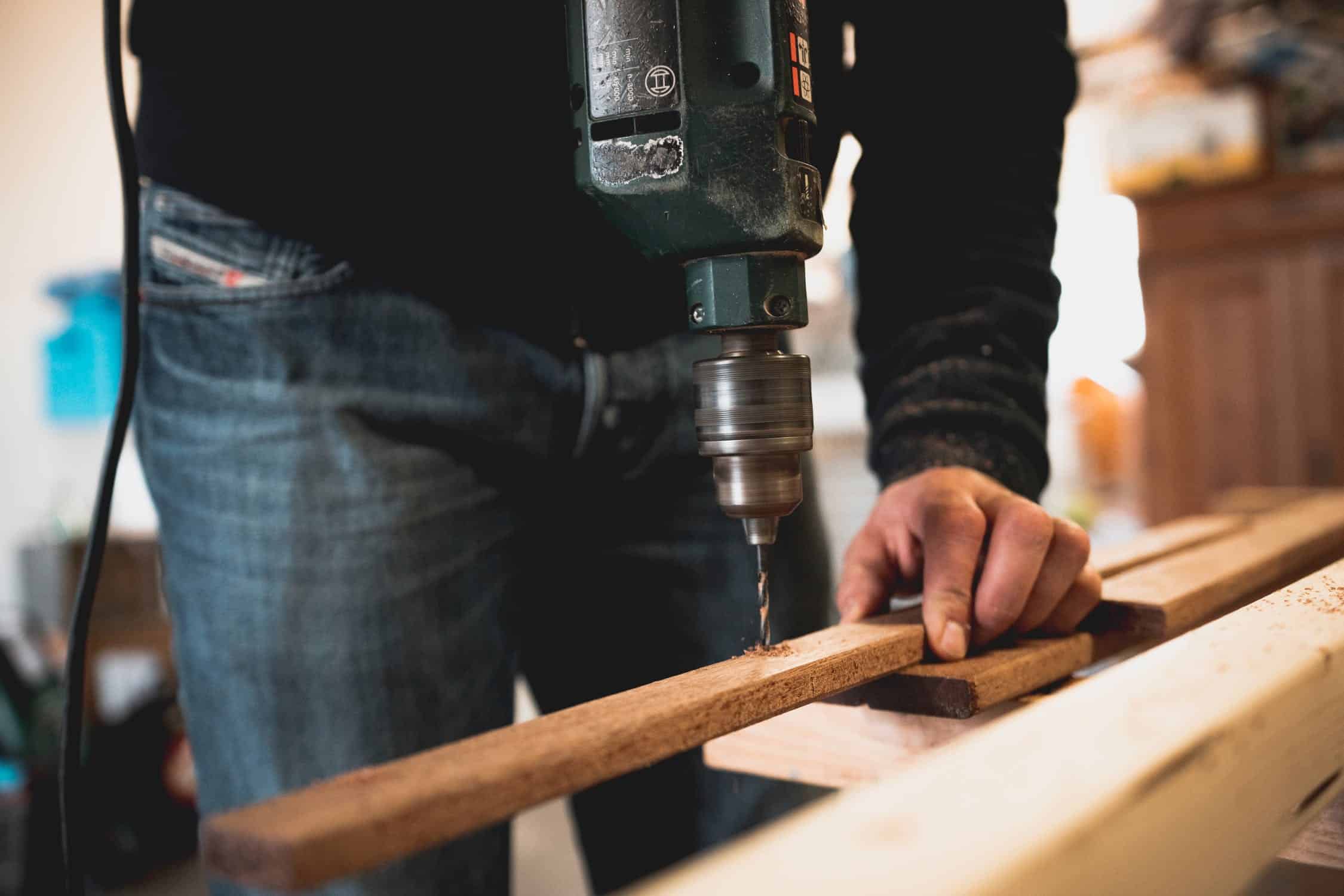 Homme qui perce une planche dans son atelier de bricolage