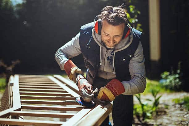 Bricoleur qui utilise une ponceuse électrique en portant un casque anti-bruit