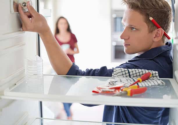 Homme qui répare l'intérieur d'un réfrégérateur