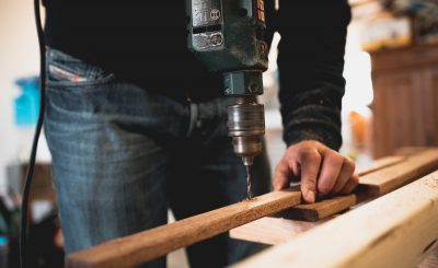 Homme qui perce une planche dans son atelier de bricolage