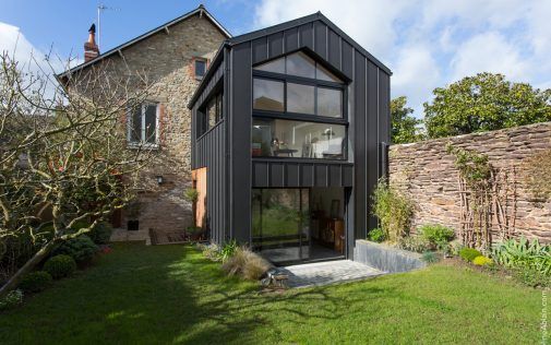 Une extension moderne à deux étages sur une maison en pierre
